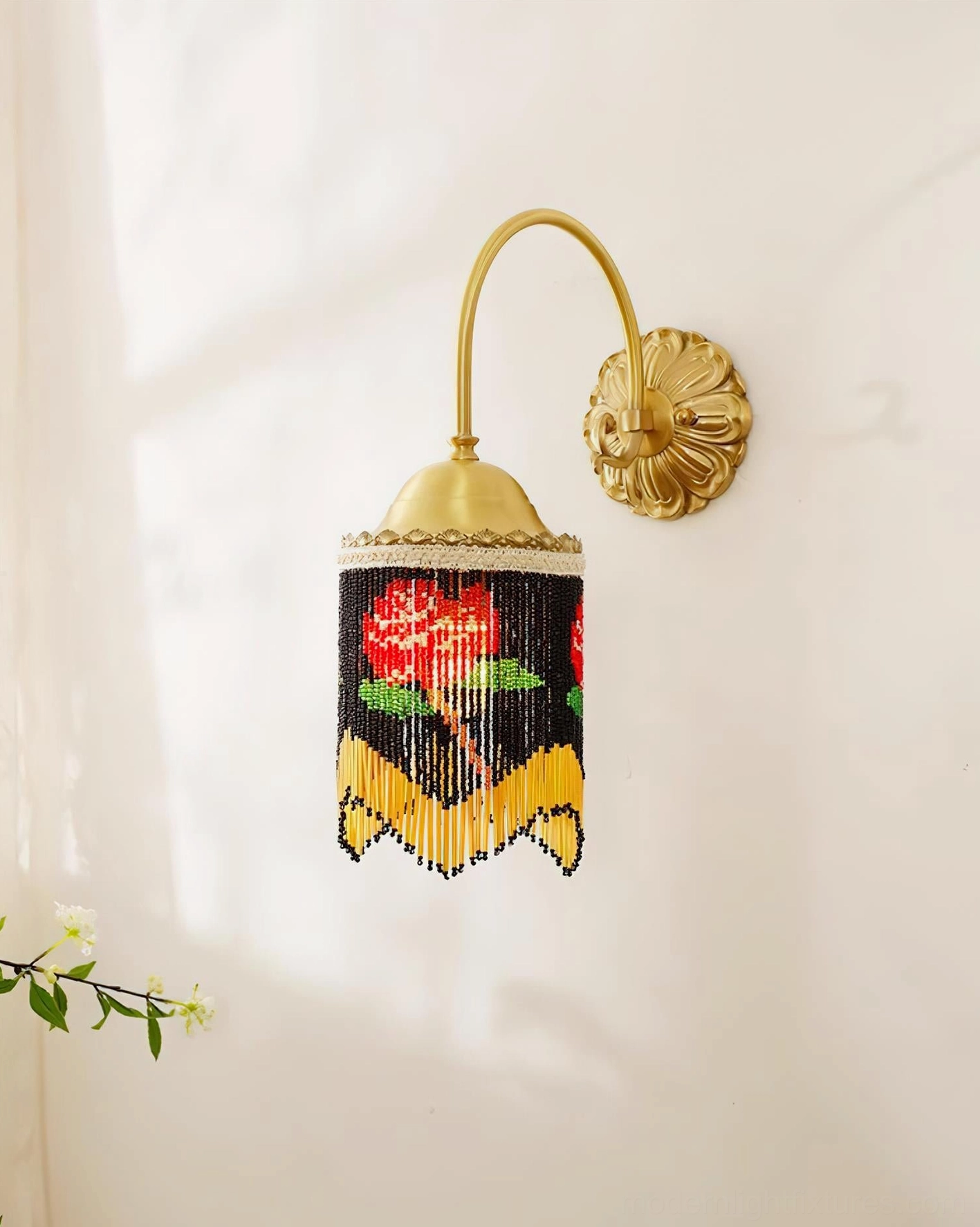 Beaded wall sconce side view featuring black rose pattern shade and polished brass hardware with small green plant decoration