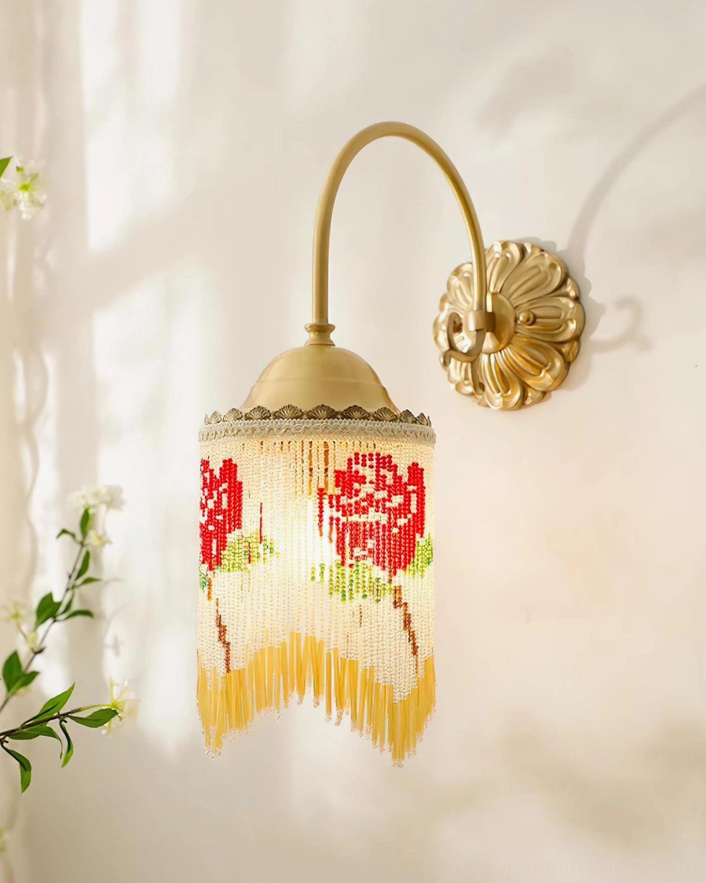 Illuminated Flamenco wall sconce with brass gold hardware yellow tassel trim and glowing beaded shade in three-quarter view