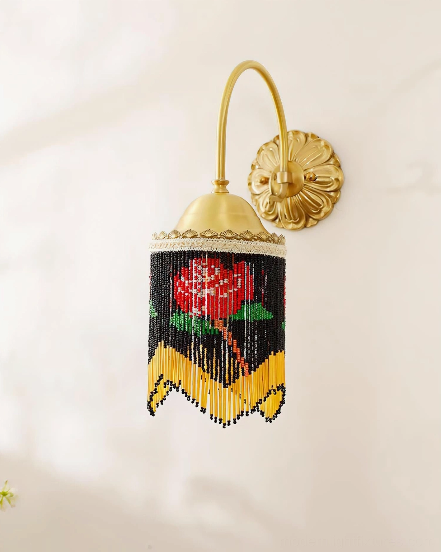 Rose beaded wall sconce with yellow tassel trim and hand-strung rose pattern photographed in warm studio lighting