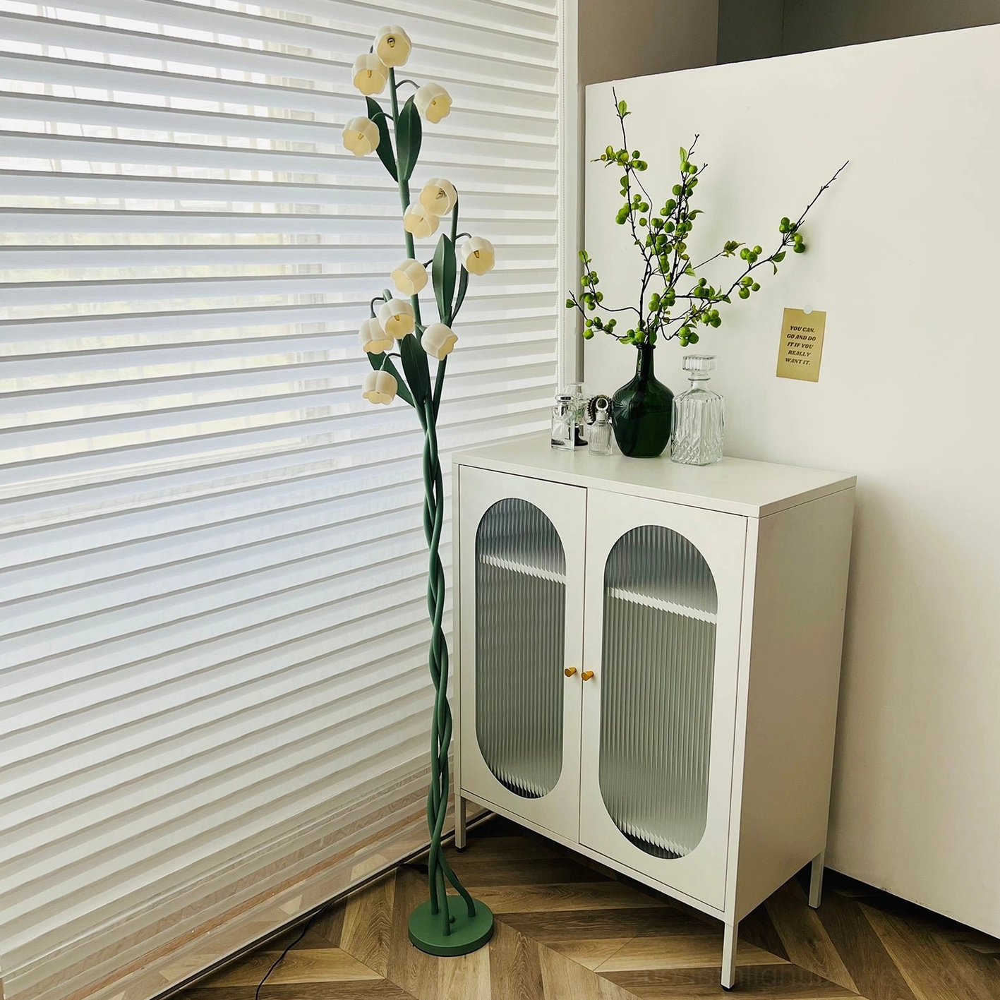 Botanical floor lamp creating ambient lighting atmosphere in contemporary interior space with green stems and white blooms