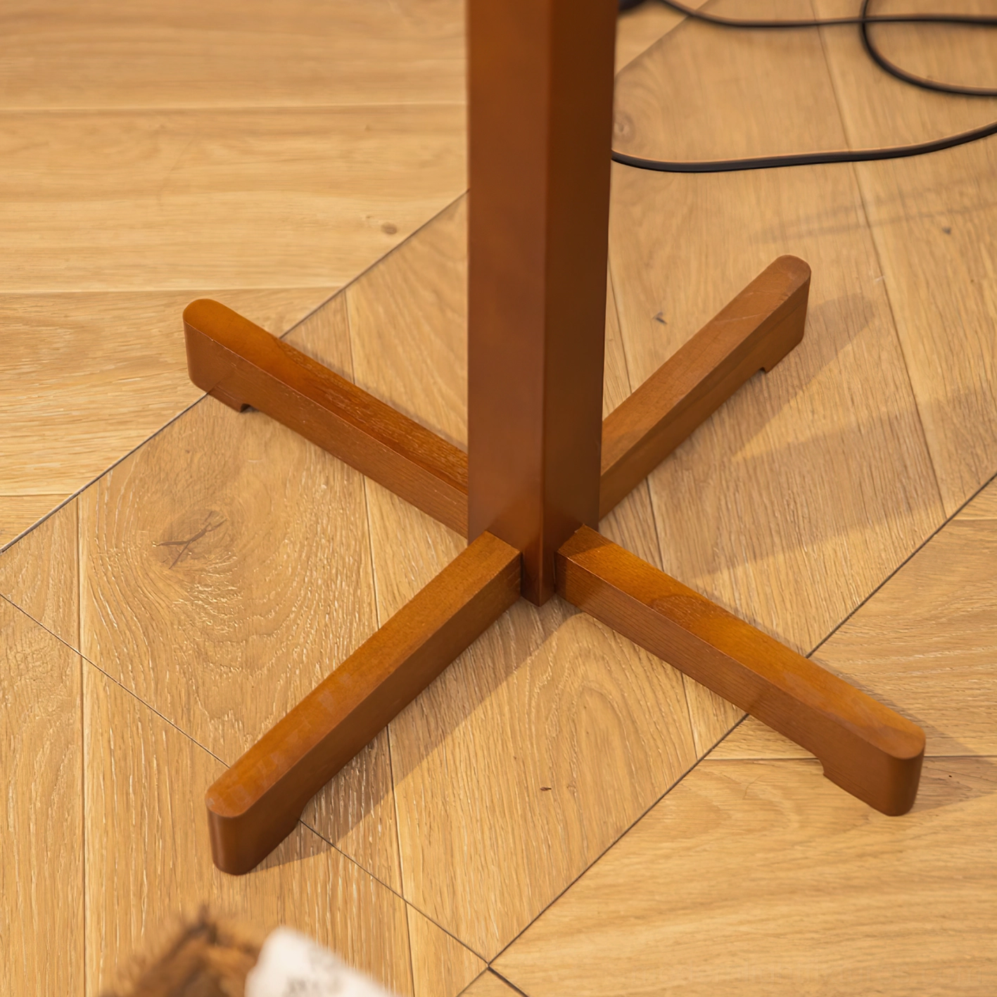 Top-down close-up view of solid wood cross base with visible grain texture and central wooden pole joint