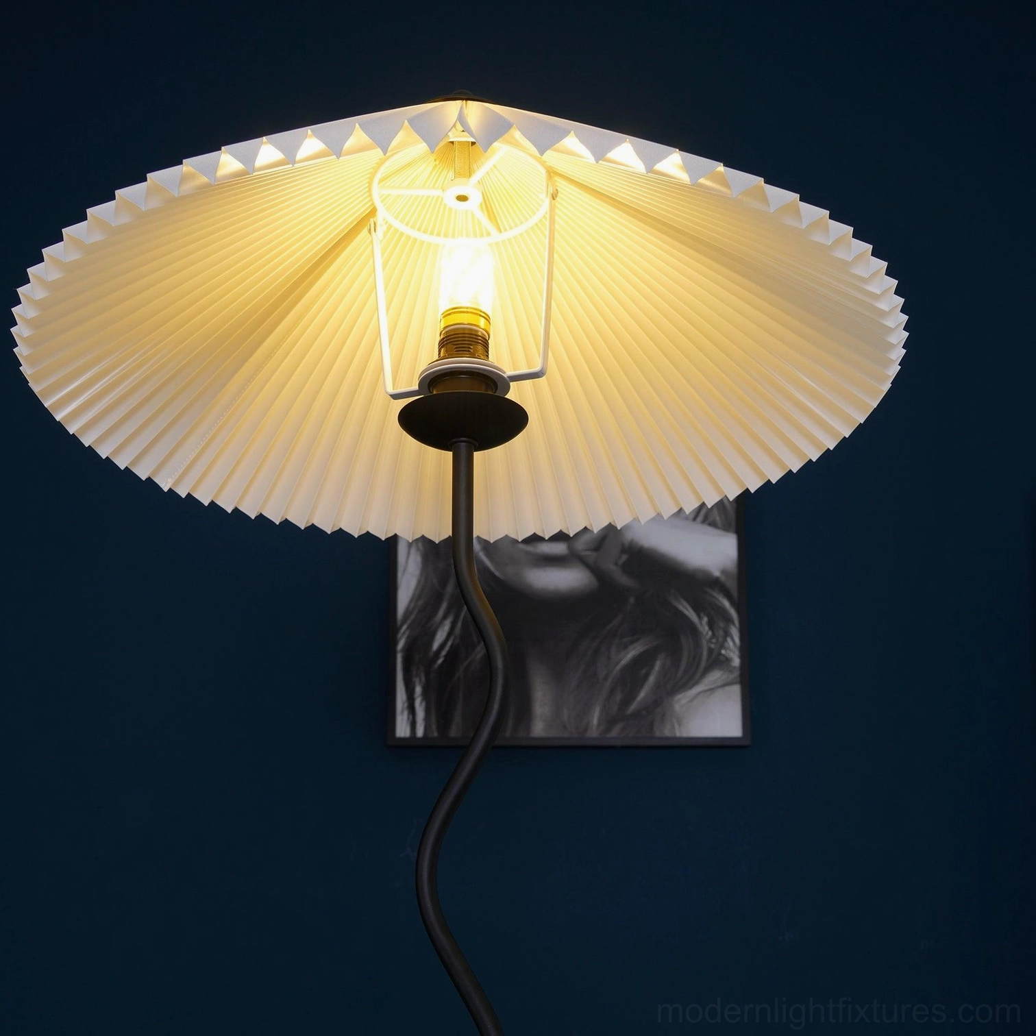 Close-up low angle view of pleated floor lamp showing exposed E14 light bulb and warm glowing illumination effect