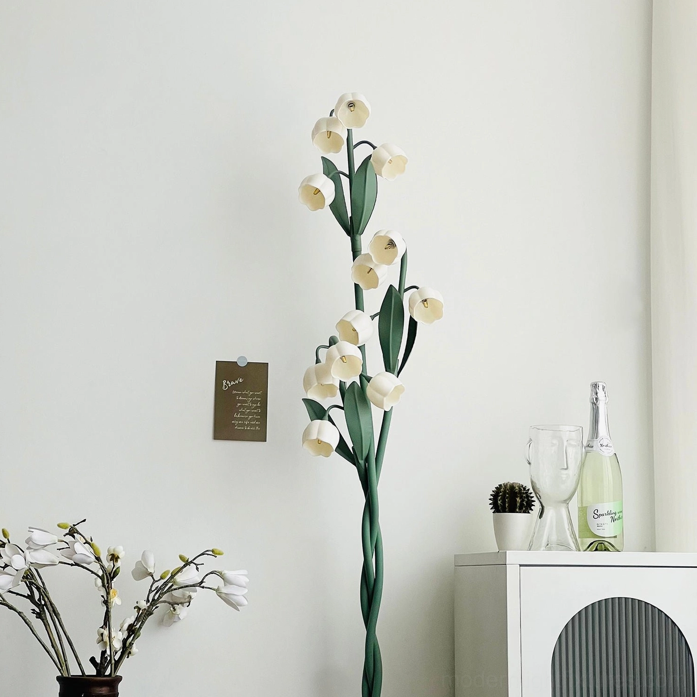 Modern floor lamp with green spiral stems and white flower heads, close-up view of design details