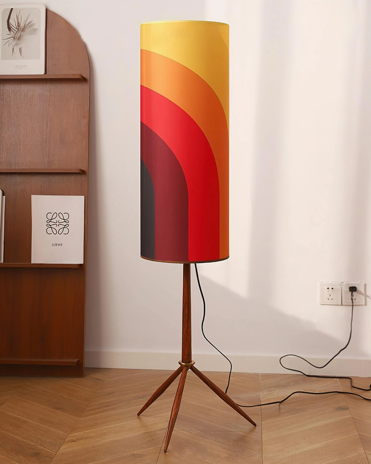 Plugged-in tripod floor lamp with extended cord positioned in home corner near wall outlet and wooden display shelf