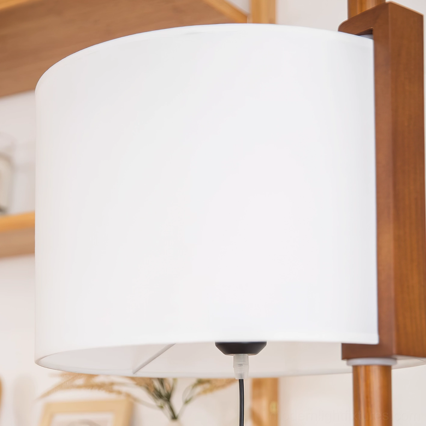 Close-up detail of white fabric cylindrical lampshade with black socket and walnut wooden pole connection