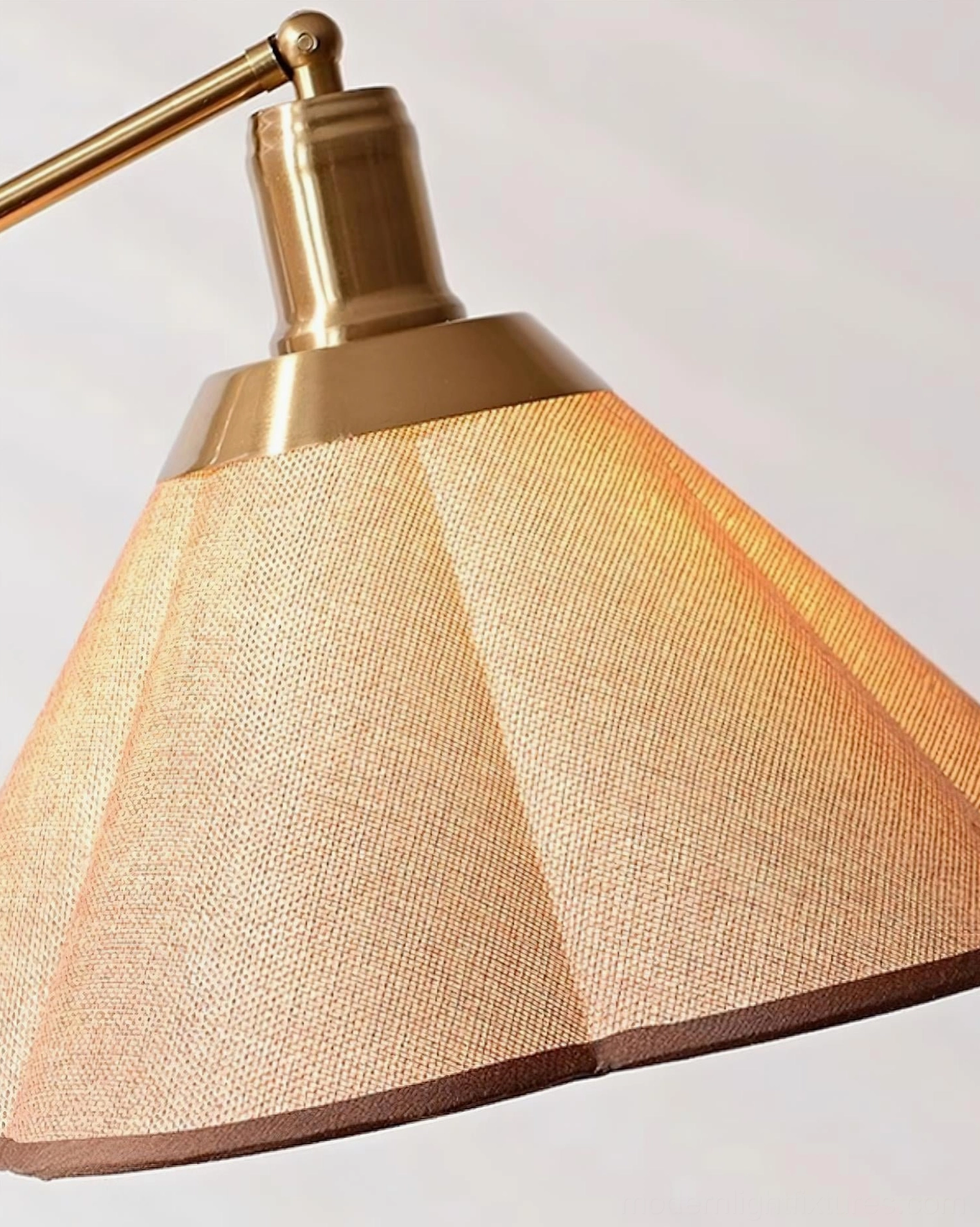 Close-up detail of swing arm floor lamp shade showing pleated woven fabric texture, brass metal lamp holder, and diffused light quality