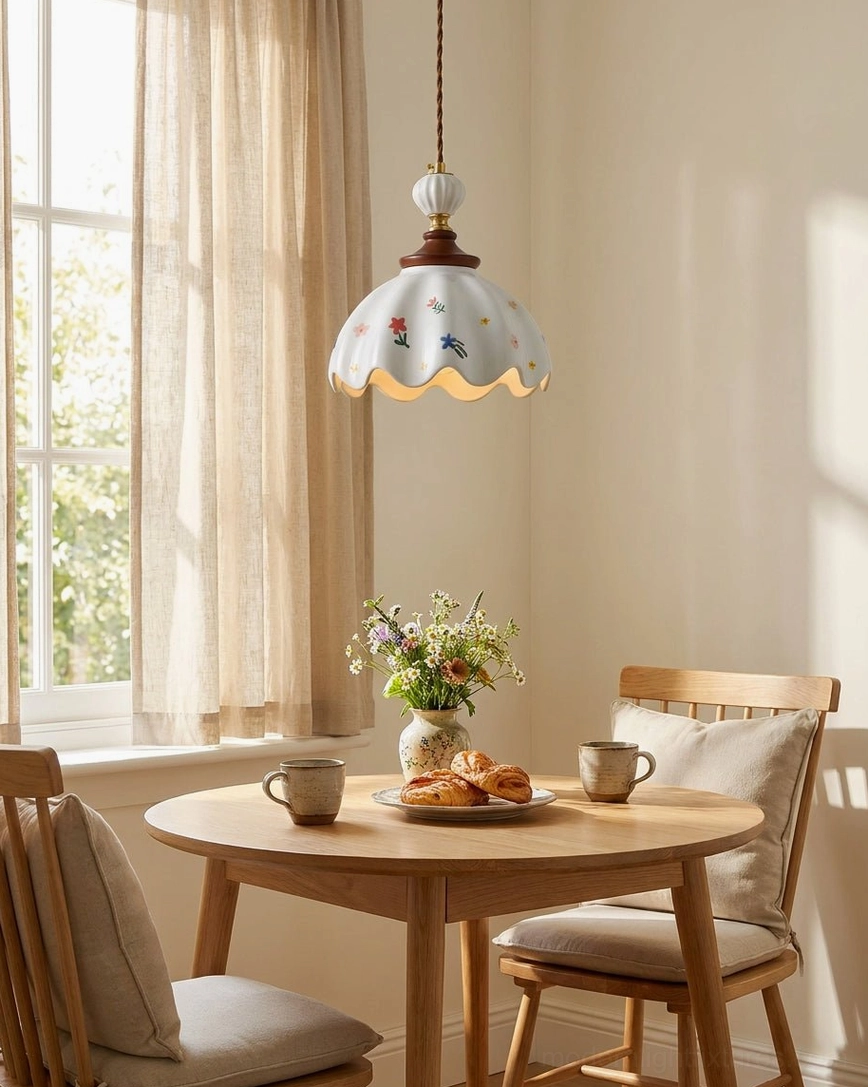Floral printed ceramic pendant illuminating window-side dining nook with wooden table, sheer linen curtains, and farmhouse decor