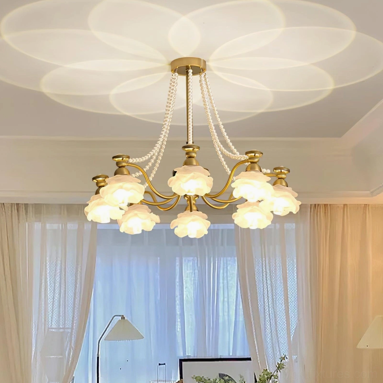 Floral chandelier with brass hardware in neutral interior space casting decorative light patterns
