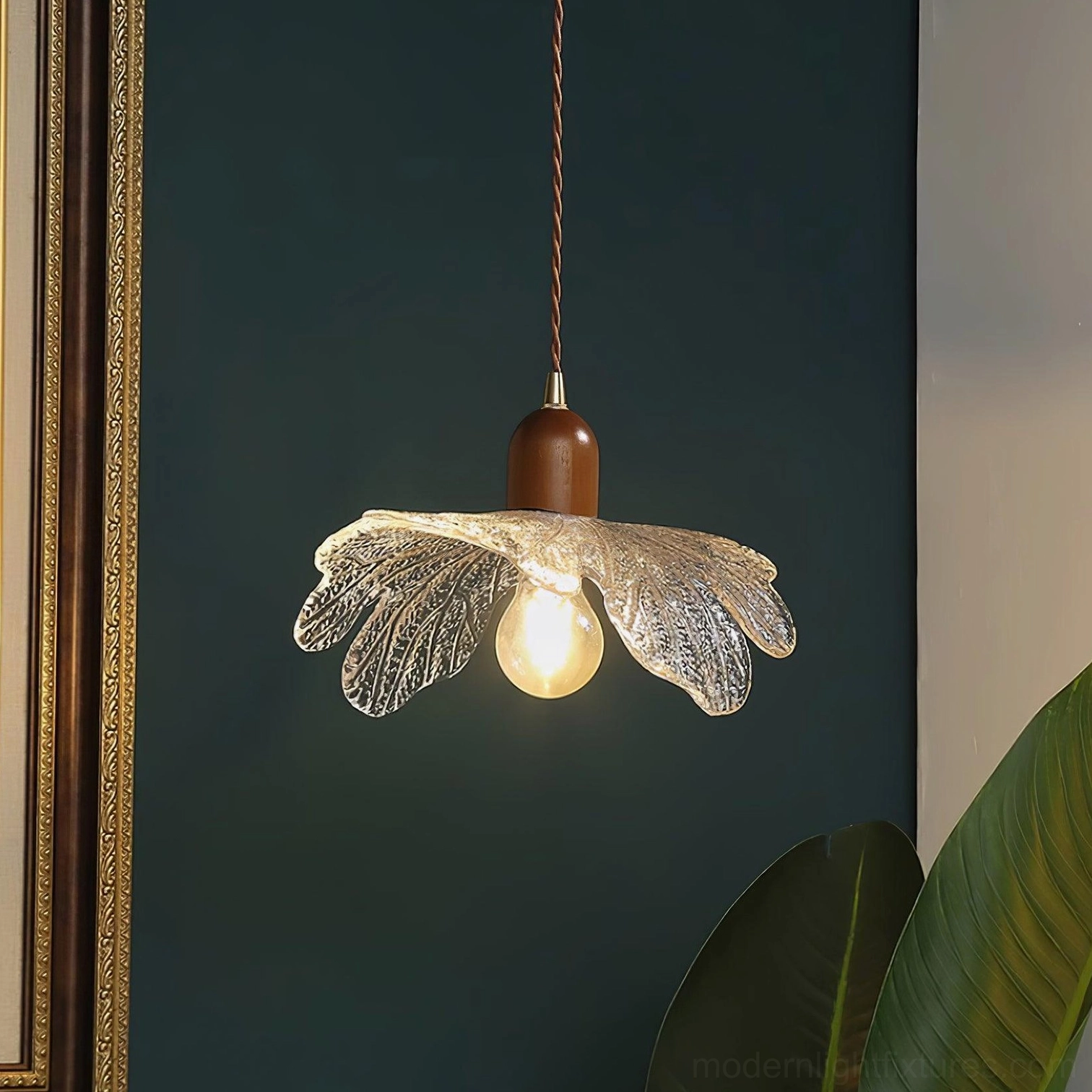 Botanical-inspired pendant fixture showing glass petal construction against dark green wall