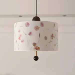 Close-up detail of Petalune pendant lamp showing pressed-petal texture, botanical specimens, textured acrylic shade with brass rod accent
