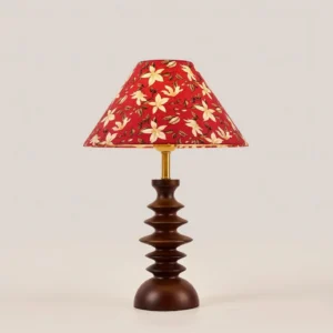 Floral red lampshade table lamp with sculptural wooden base, angled studio view