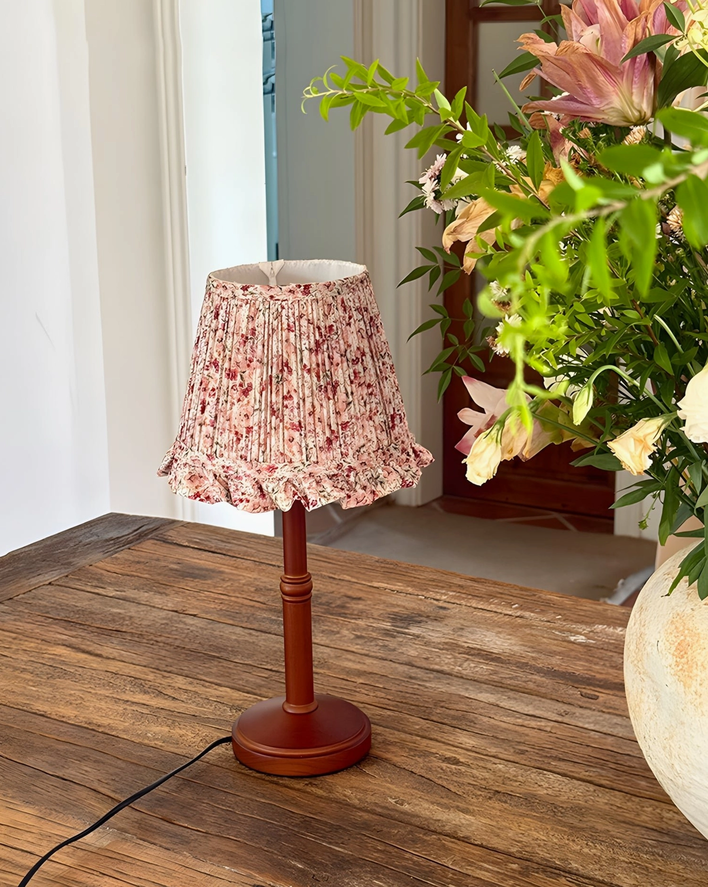 Floral ruffle shade table lamp on wooden side table with rustic home decor and indoor plants