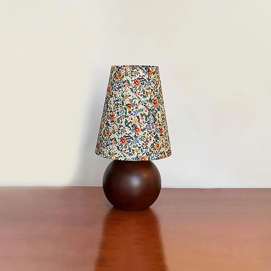 Botanical floral table lamp with spherical wooden base on polished wooden tabletop