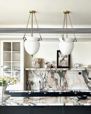 Paired white frosted glass Florko pendant lights hanging above luxury marble kitchen island, contemporary dining setup