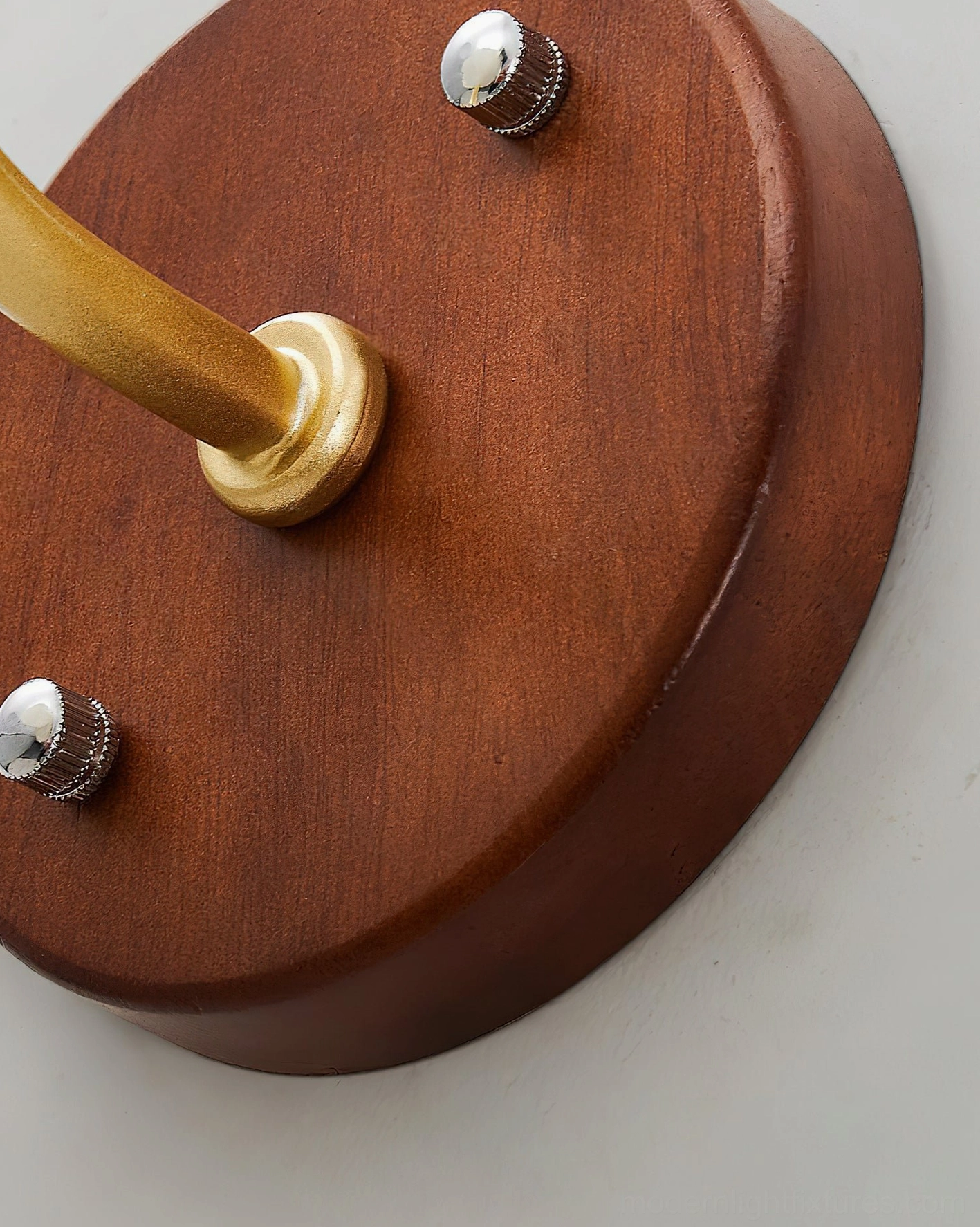 Florvia wall lamp mounting hardware close-up, showing walnut wood backing plate and brass arm with installation screws