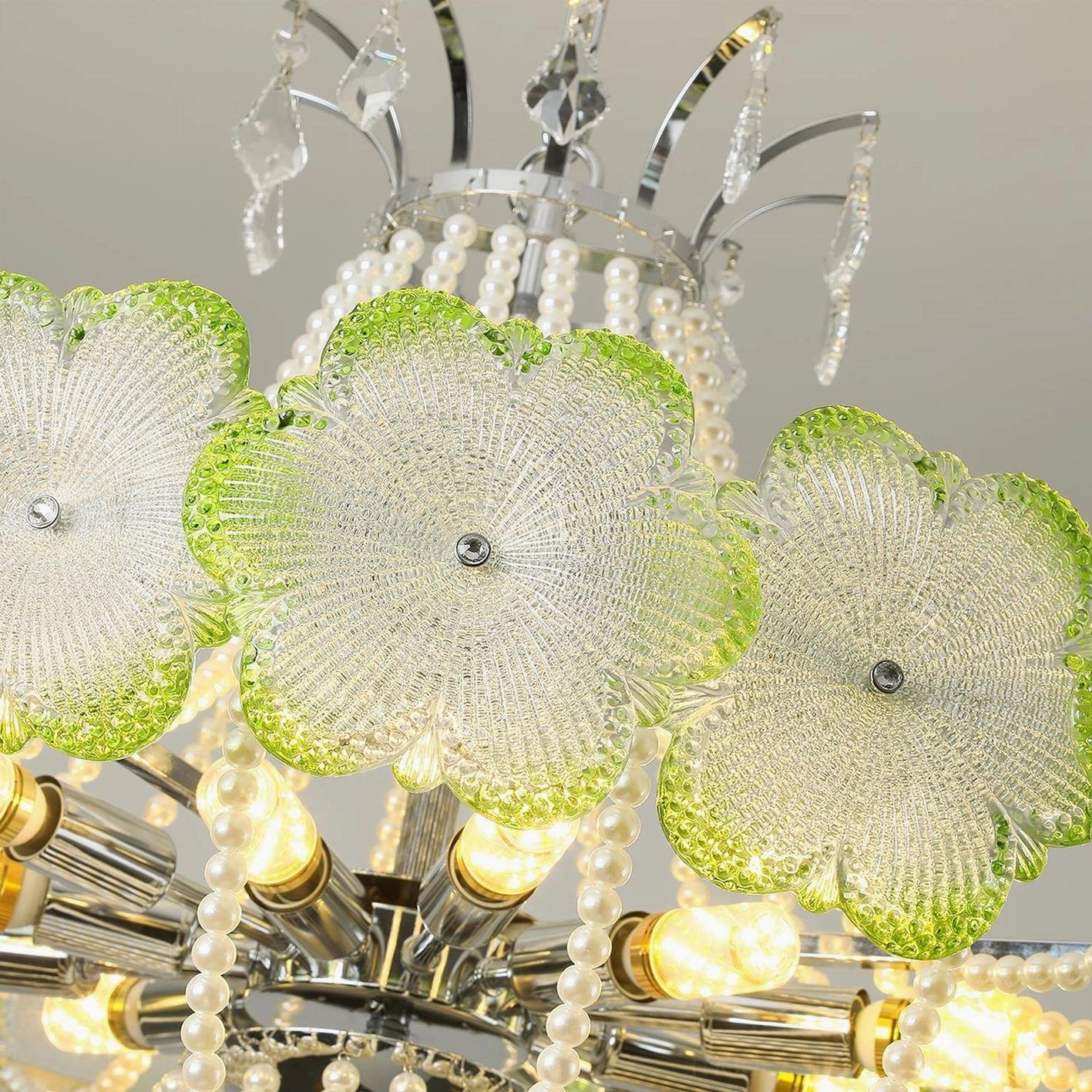 Close-up detail view of flower glass shade with green trim, pearl chain, exposed bulb, and chrome lamp holder