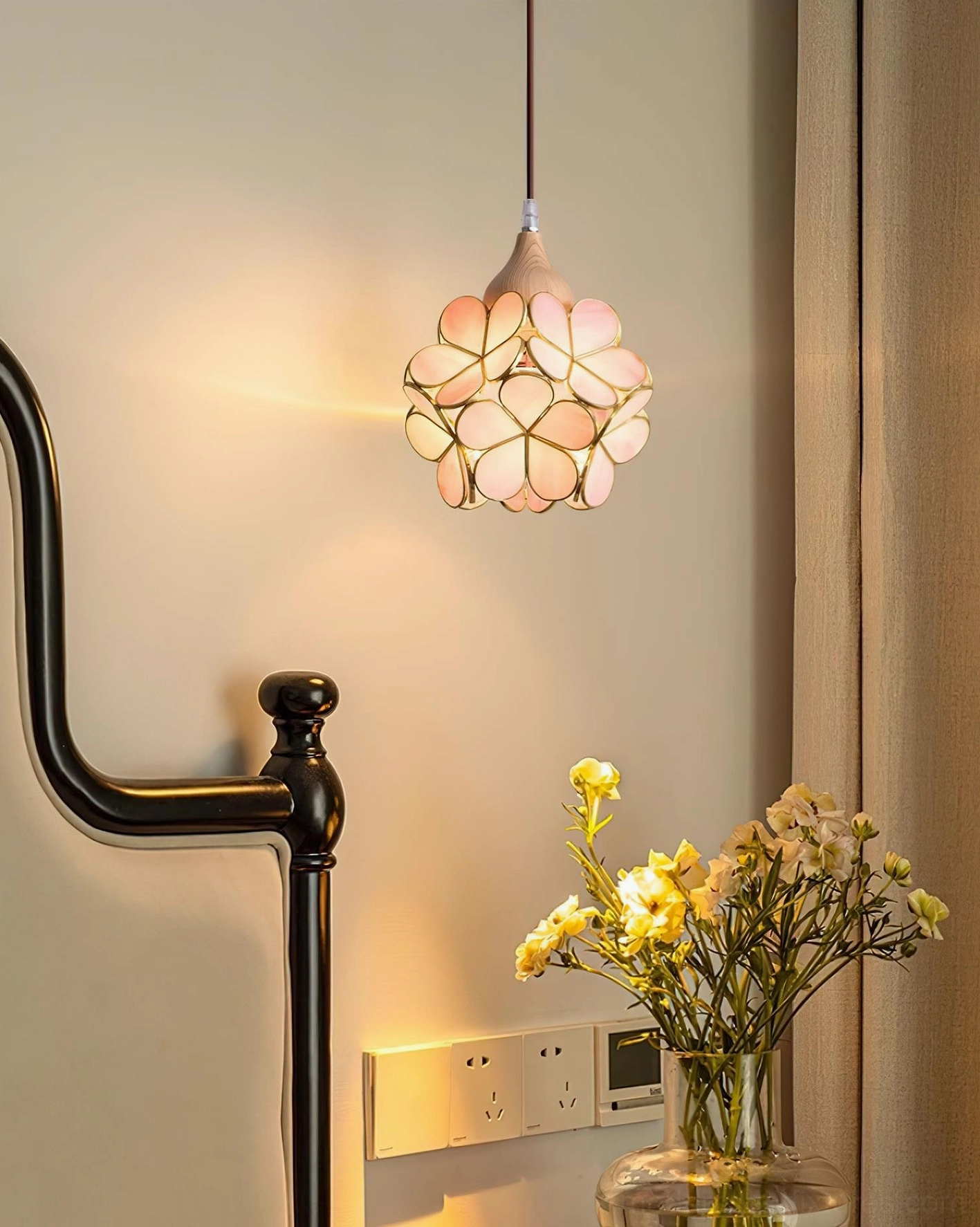 Pink stained glass flower pendant light creating warm ambiance in vintage bedroom with floral table centerpiece