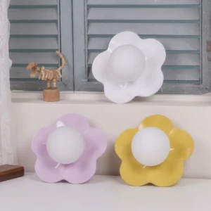 Three color variants of flower wall sconces displayed on table, white pink and yellow botanical lamps