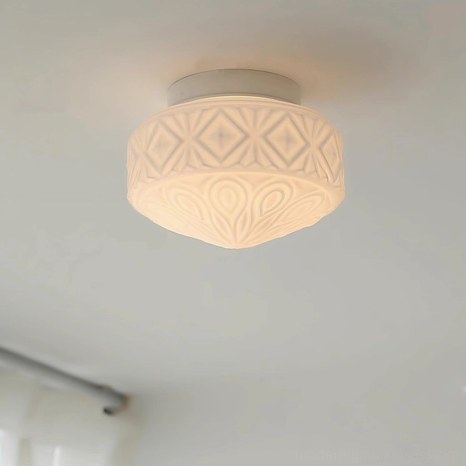 Flush mount carved glass ceiling light with radial embossed pattern, showing light diffusion through textured glass surface