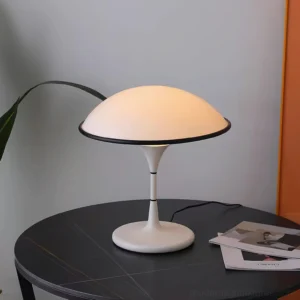 Fontana mid-century modern table lamp three-quarter view on dark round side table with magazines
