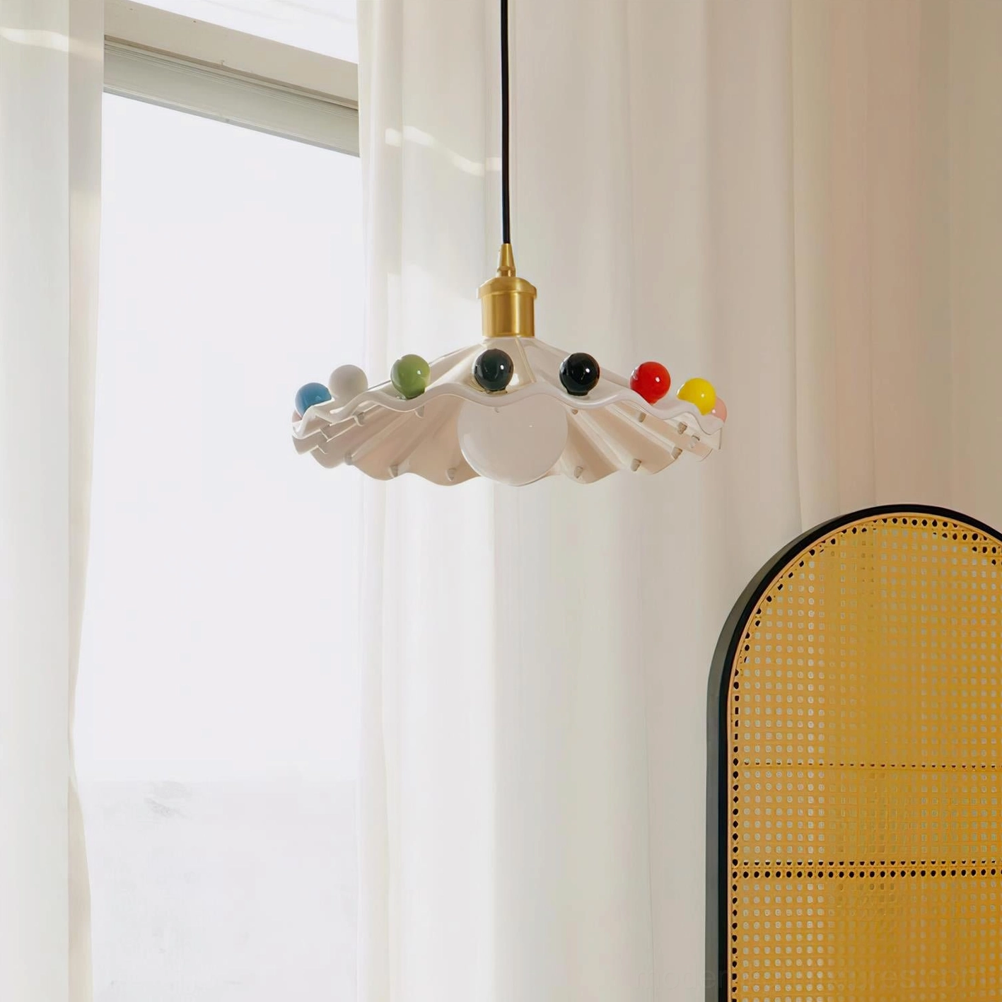 Fonthill ceramic scalloped pendant lamp hanging in modern interior with sheer curtains and rattan furniture warm lighting
