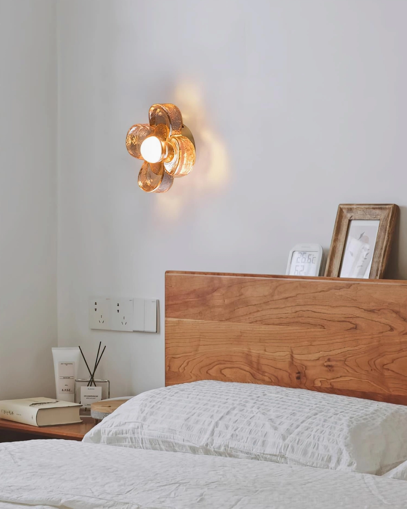 Four-leaf clover wall-mounted ceiling light installed in bedroom above wooden bed frame with warm white glow