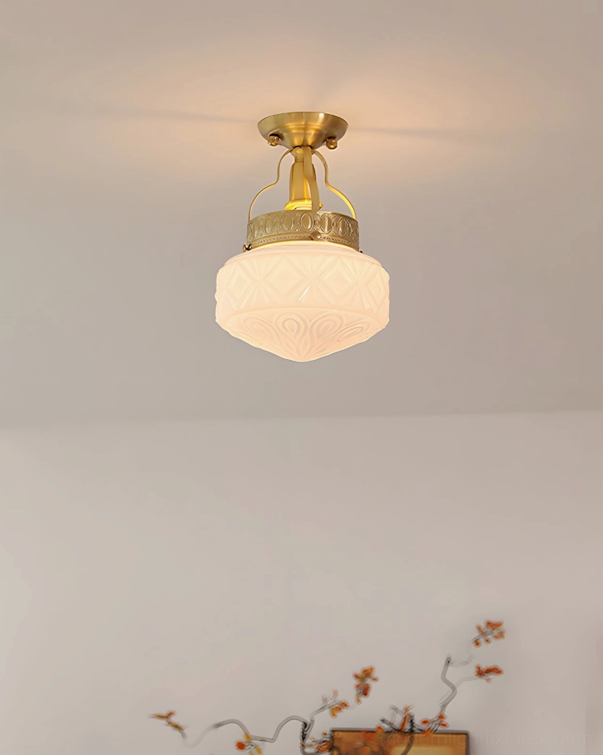 Low-angle upward view of semi-flush ceiling lamp with frosted carved glass shade and brass gold base