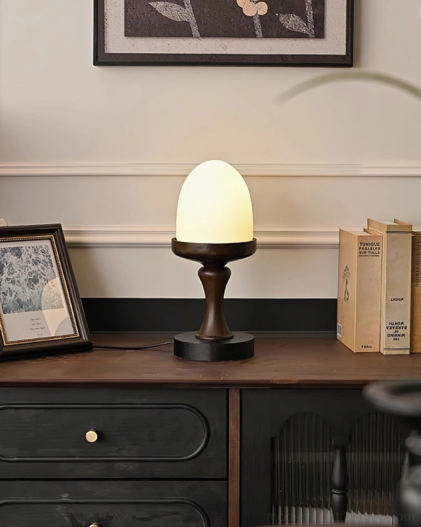 Illuminated organic frosted glass lamp base on retro wooden sideboard with decorative styling, three-quarter angle