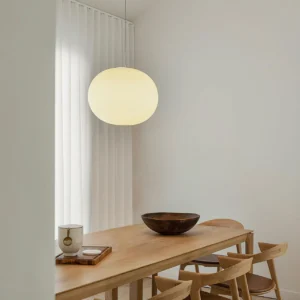 Frosted sphere pendant light installed above dining table in Scandinavian minimalist interior - warm white lighting in residential dining room