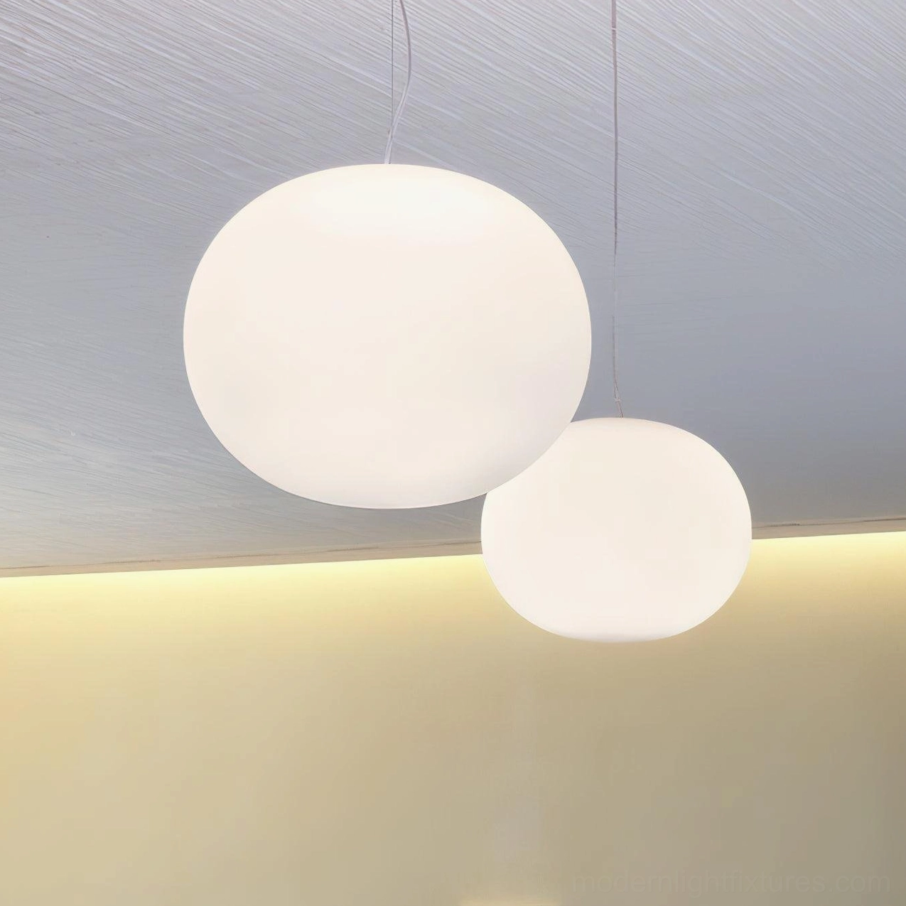 Two different sized frosted glass sphere pendant lamps - minimalist modern lighting displaying compact and statement sizes