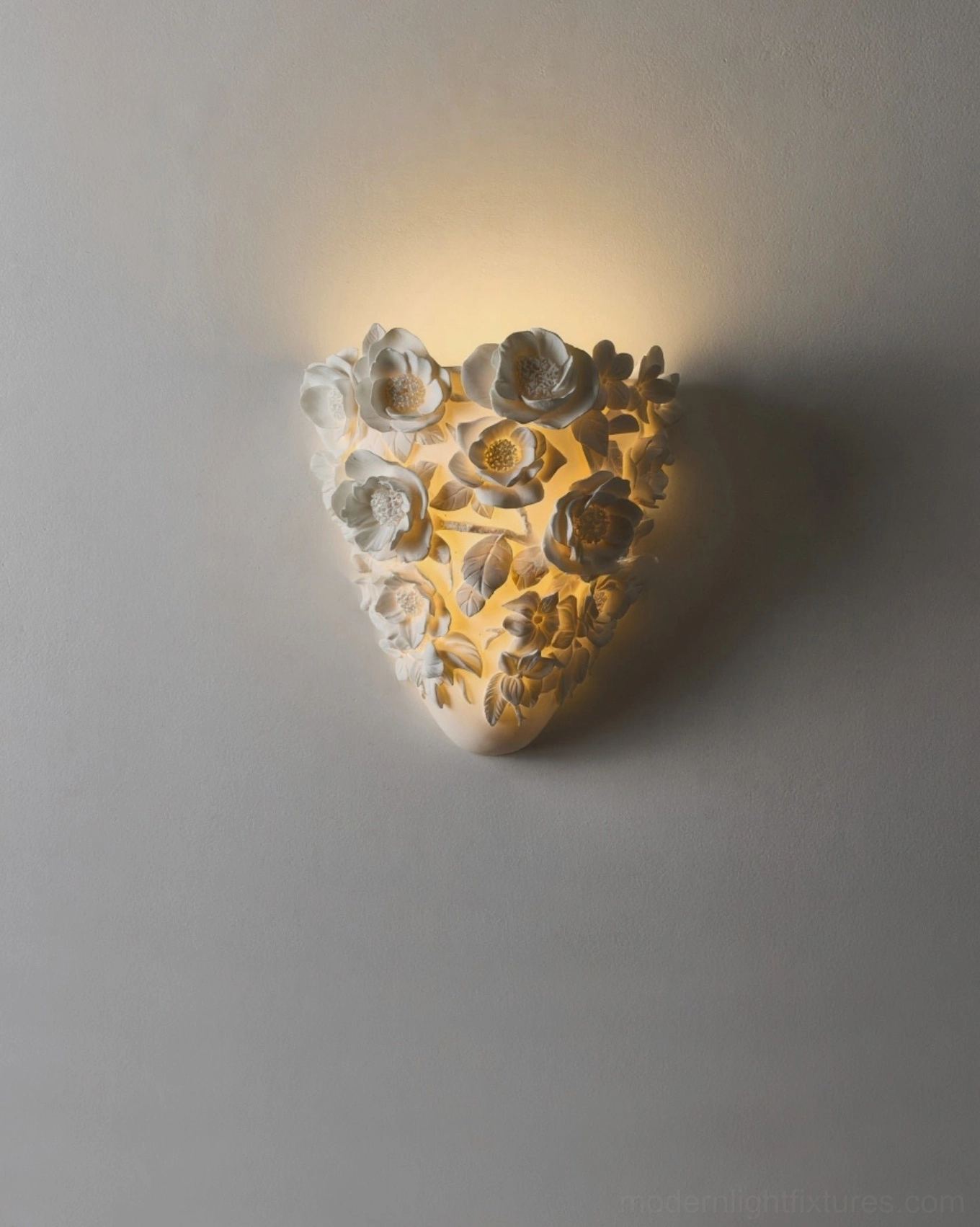 Illuminated gardenia wall sconce with warm amber glow, detailed ceramic flower relief close-up