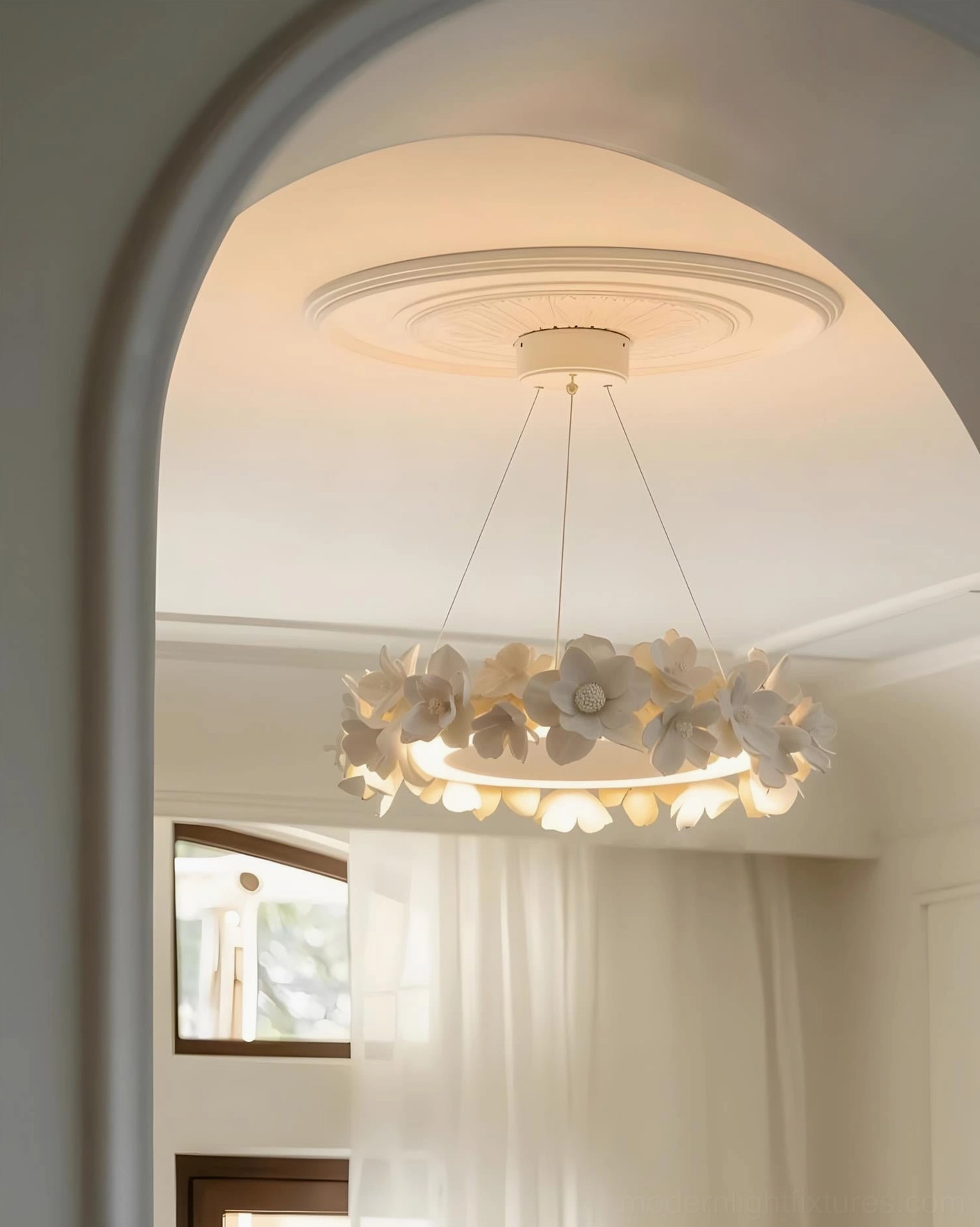 Modern chandelier with creamy artificial gardenia petals hung in French-style residential interior through arched doorway with warm ambient lighting