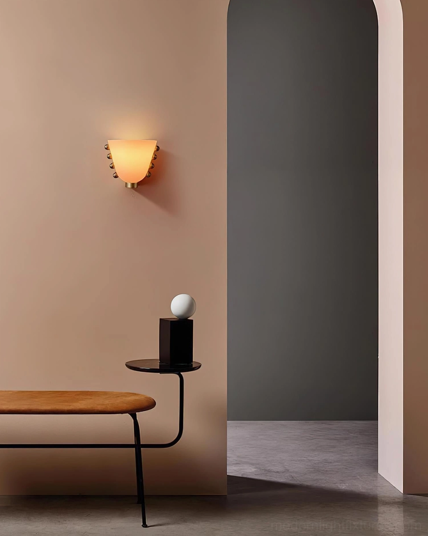Gemma frosted glass wall sconce with warm amber light and brass mounting hardware on beige residential wall