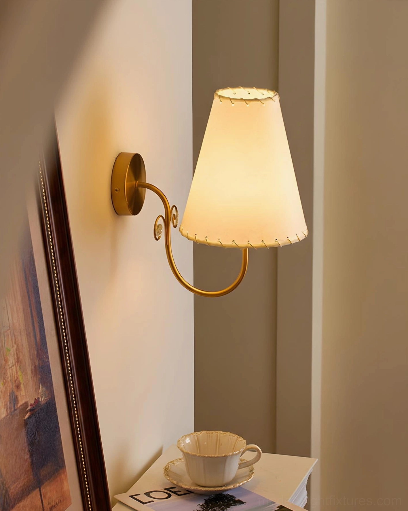 Gentle Bend wall sconce lit warm beige shade in hallway with framed artwork and home decor styling