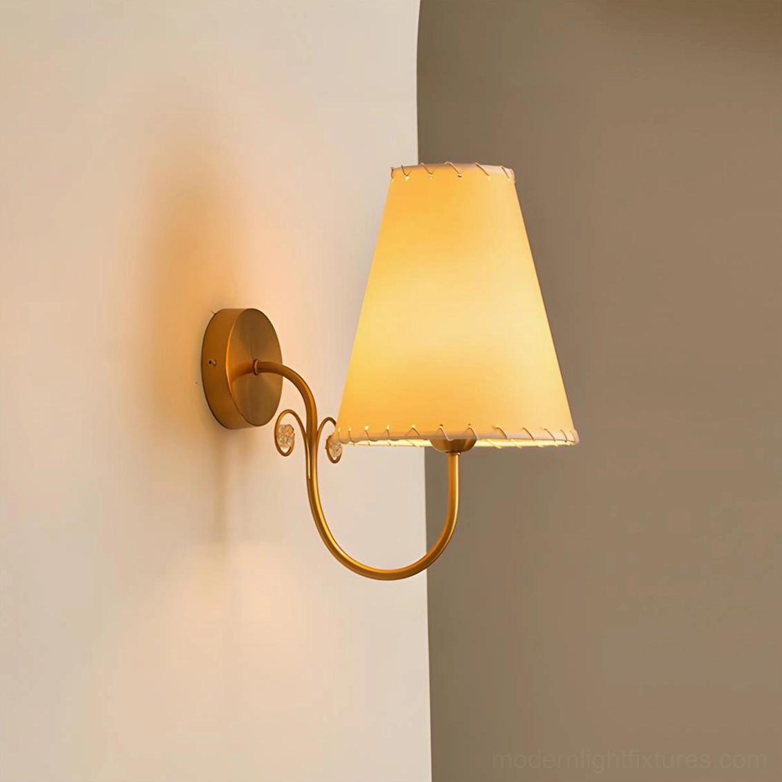 Gentle Bend wall sconce side angle lit warm beige fabric shade brass scroll curved arm detail