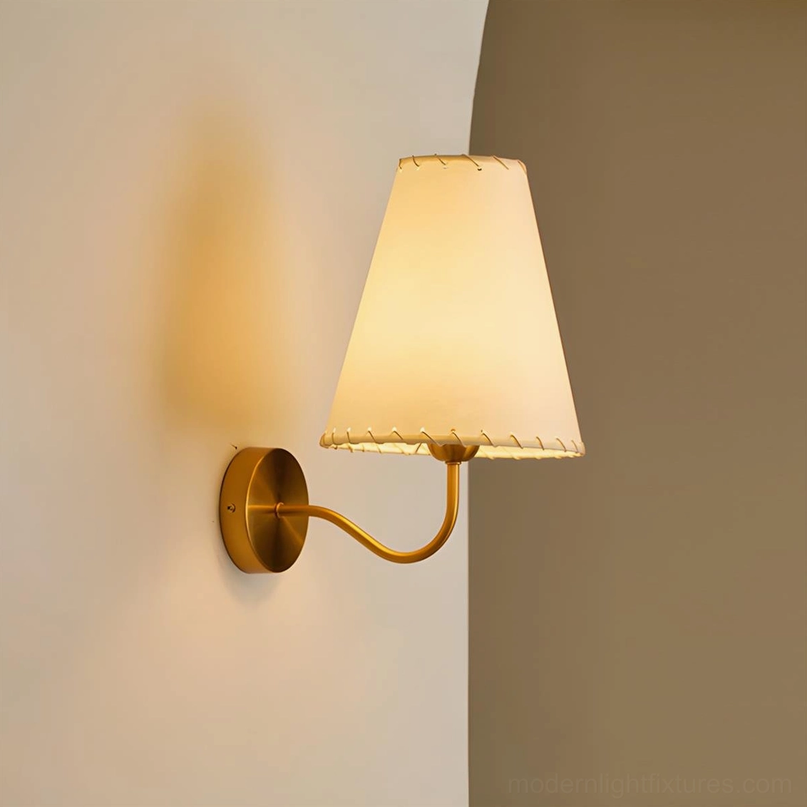 Gentle Bend wall sconce flat side view lit warm beige conical fabric shade brass curved arm