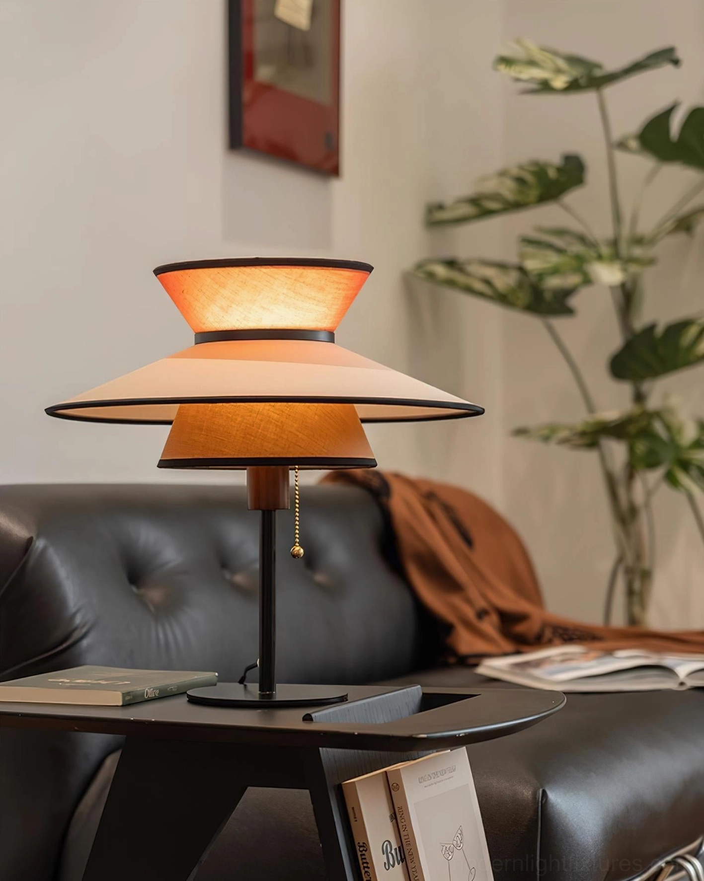 Contemporary geometric table lamp with illuminated multi-tier fabric shade casting warm light in modern living room lounge interior setting