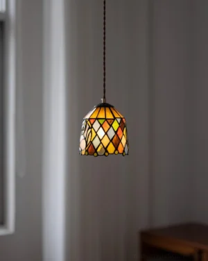 Hanging stained glass pendant lamp with geometric diamond pattern and warm retro aesthetic in home interior