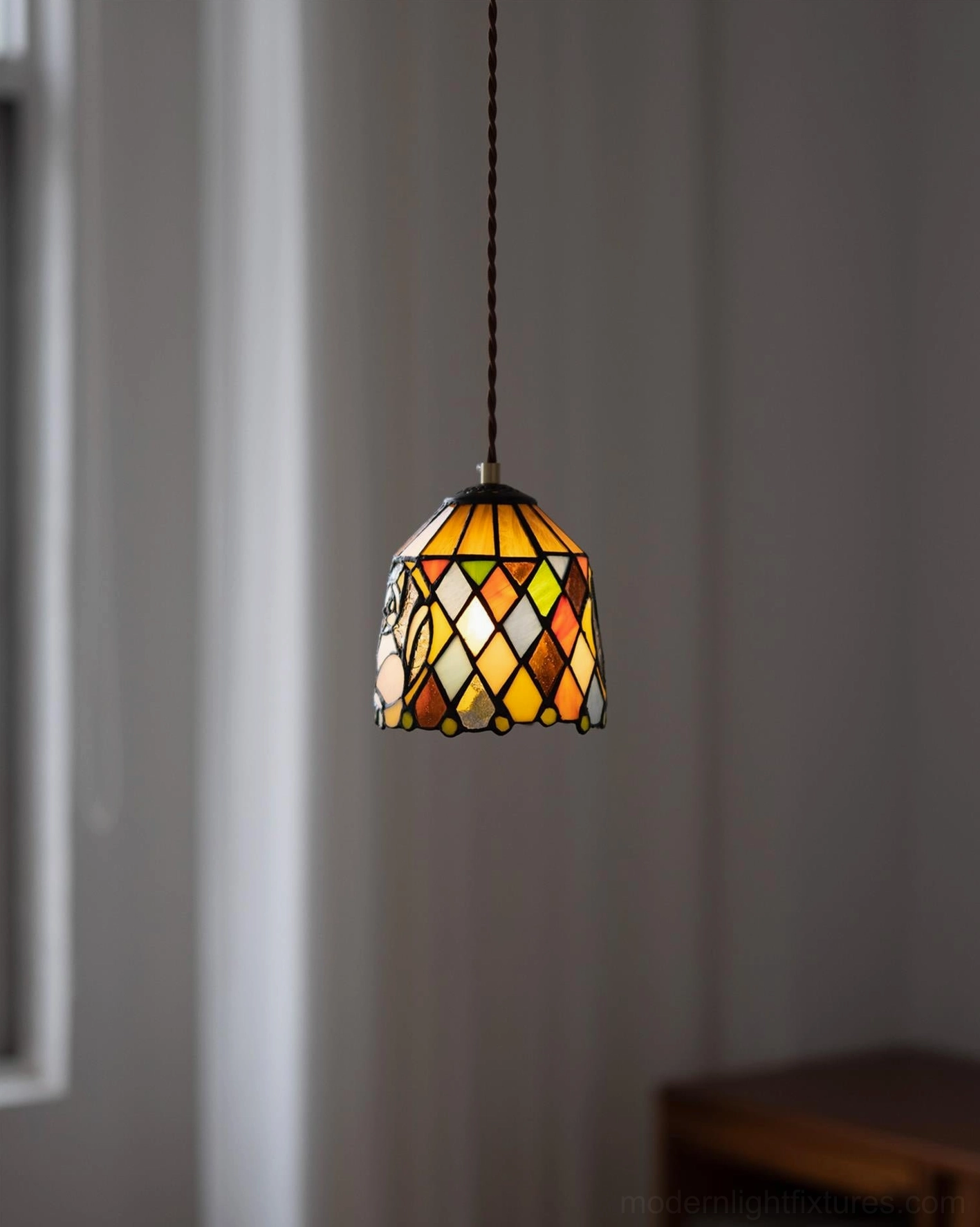 Hanging stained glass pendant lamp with geometric diamond pattern and warm retro aesthetic in home interior