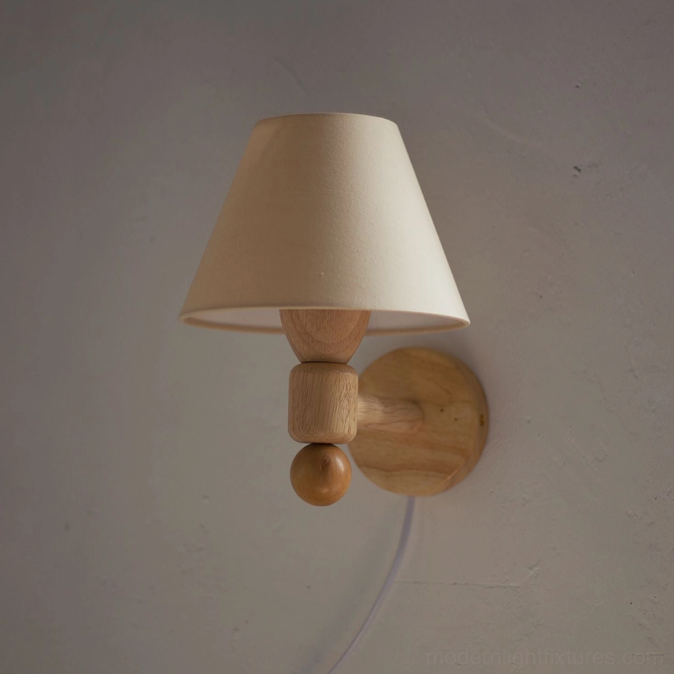 Close-up front view of geometric wall sconce with conical beige shade and sculptural wood arm featuring round decorative element