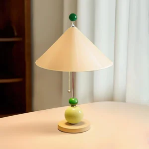 Modern geometric table lamp displayed on light desk with green sphere base and metal pull chain