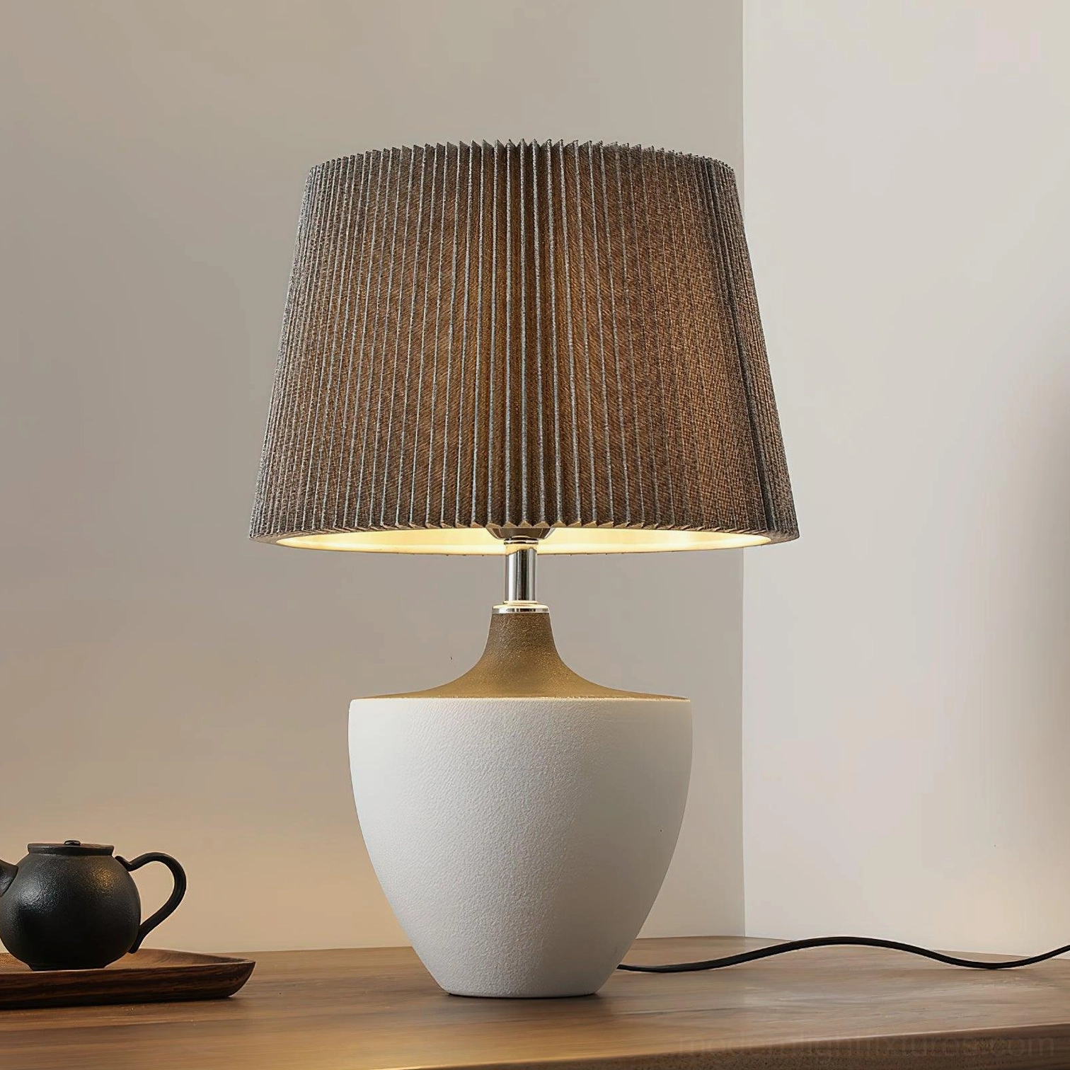 Ghassan illuminated ceramic table lamp on wooden furniture with chrome metal neck and brown pleated shade