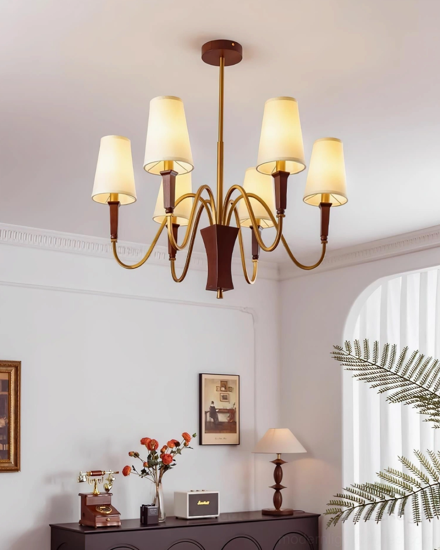 Gianna 8-light chandelier side view showcasing dark wood base and flowing brass metal arms in classic American home