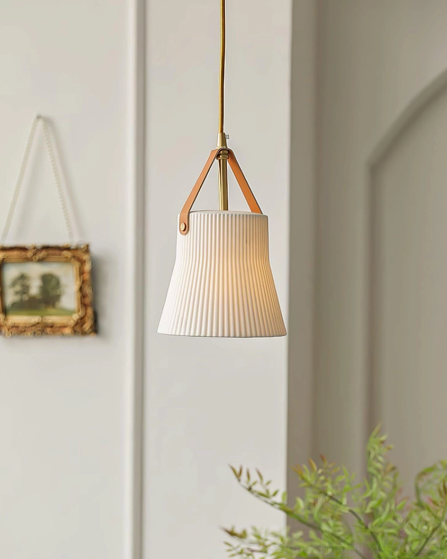 Slim ceramic ridged pendant lamp suspended in hallway with arched wall trim and leather suspension strap visible