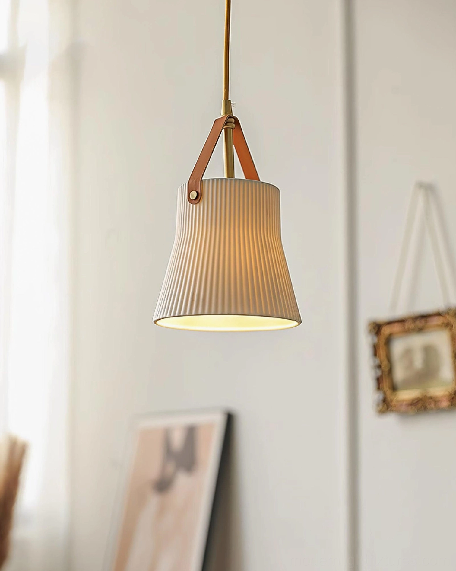 Compact ceramic ridged pendant light creating warm glow in room with framed wall art and minimalist decor