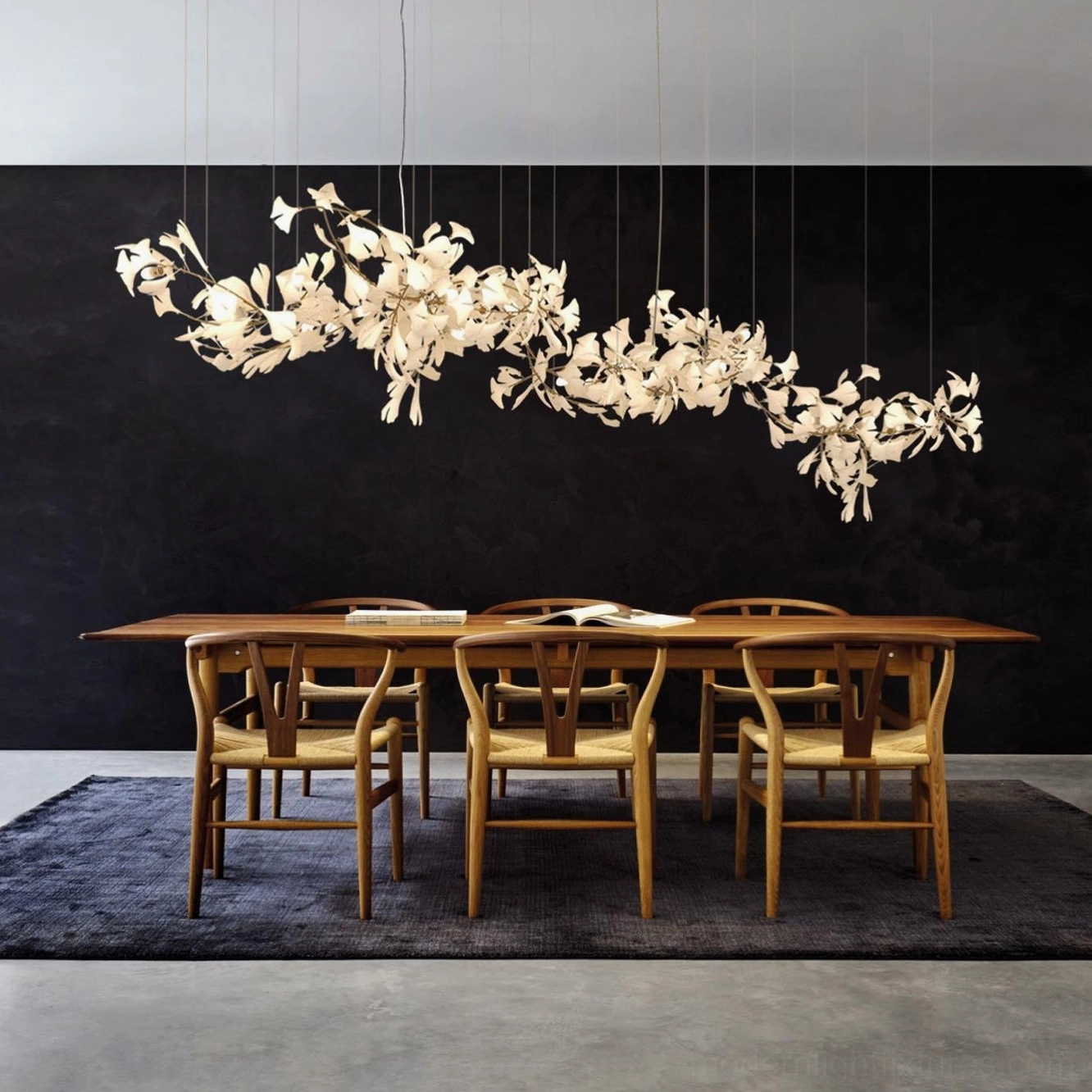Ginkgo leaf chandelier installed above dining table with asymmetrical cream leaf design and dark accent wall backdrop