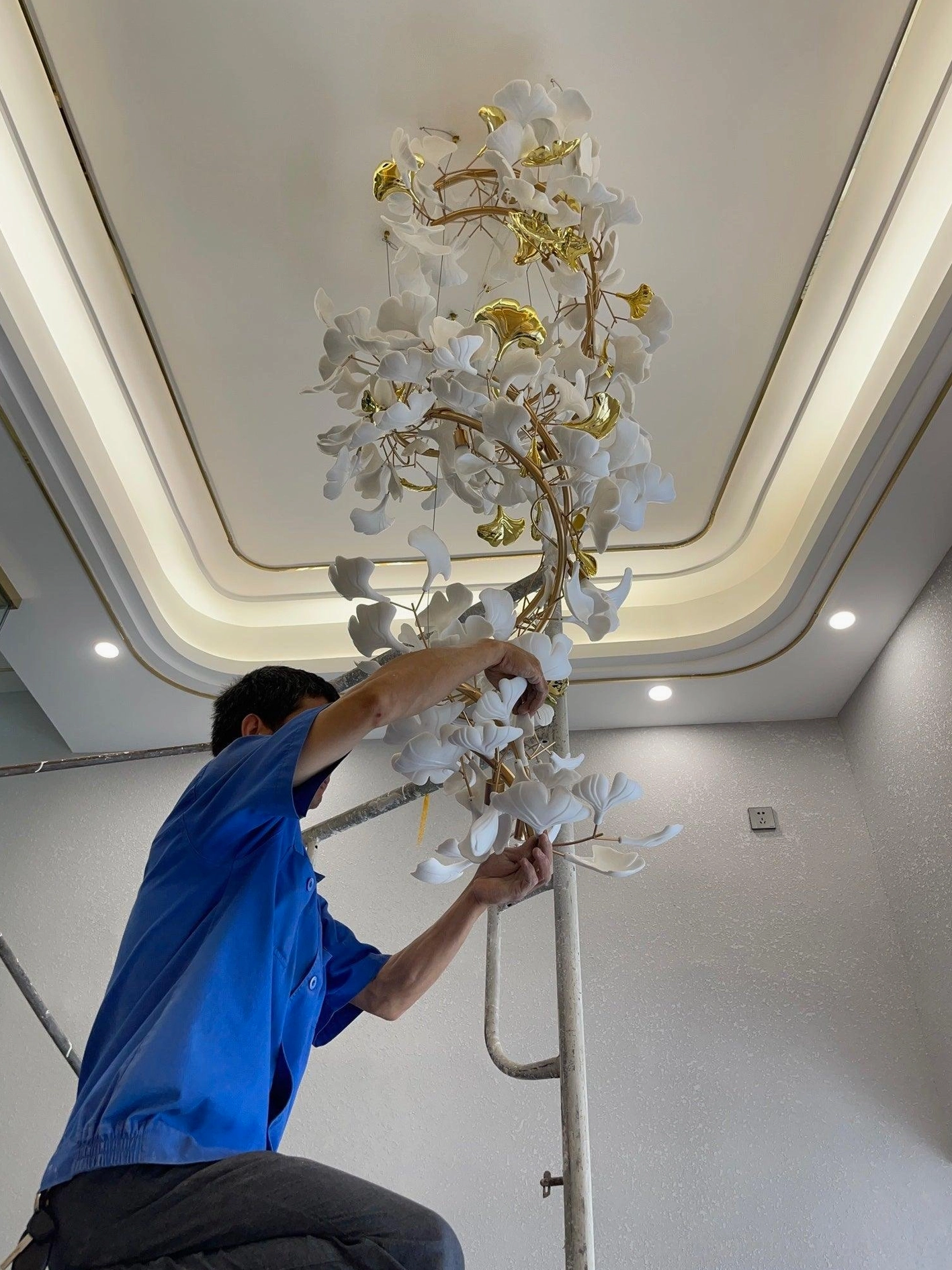 Installation detail of ginkgo leaf chandelier showing metal branch connections and ceramic leaf attachment points