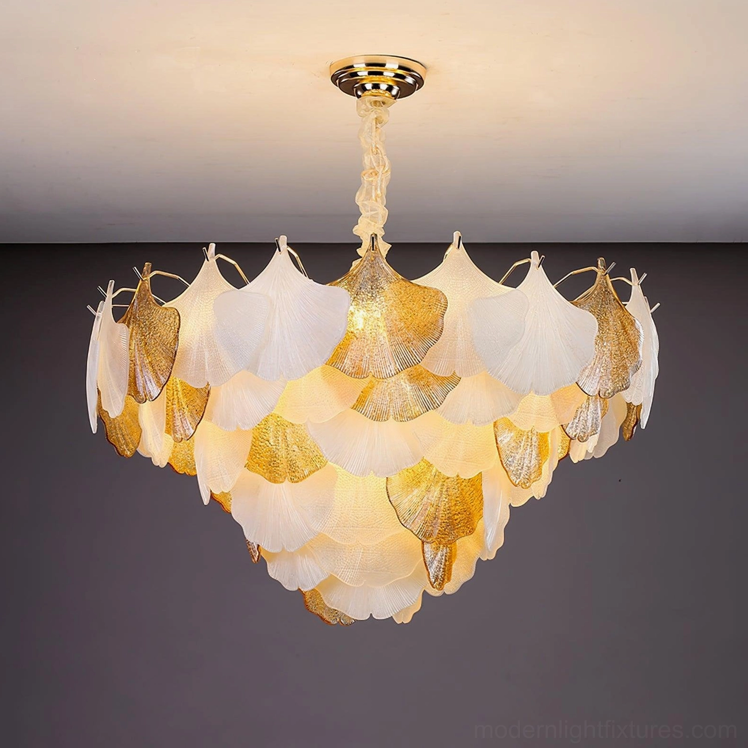 Three-quarter front view of ginkgo chandelier with warm glowing light through layered white and gold petals