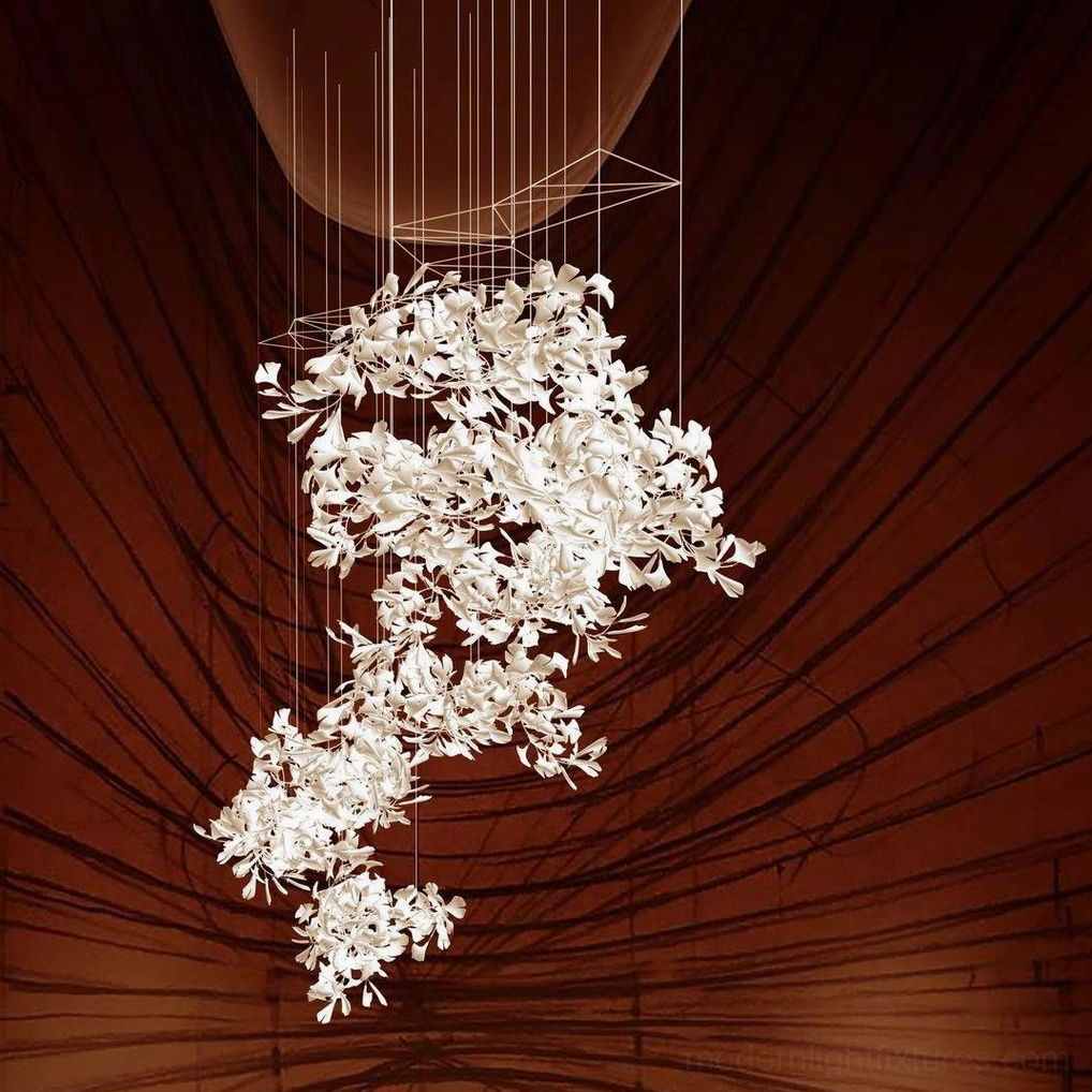 Ginkgo leaf chandelier suspended by thin wires in red wood-paneled space with bright white glowing leaves