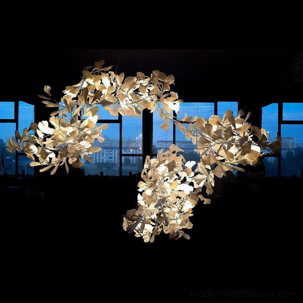 Close-up view of ginkgo leaf chandelier with gold-toned ceramic leaves and warm ambient light against dark background